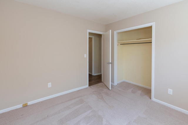 unfurnished bedroom featuring light carpet, baseboards, and a closet