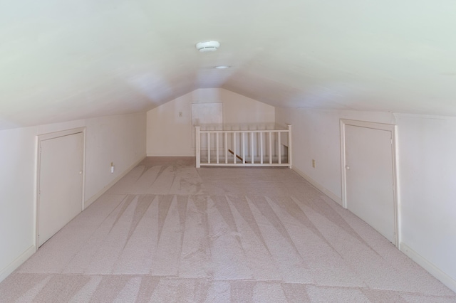 additional living space featuring lofted ceiling, light colored carpet, and baseboards