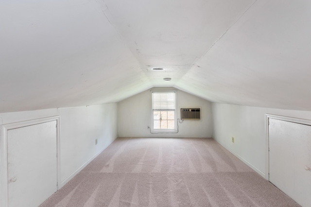 bonus room with baseboards, vaulted ceiling, an AC wall unit, and light colored carpet