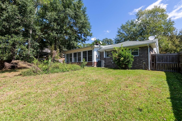 back of house with a yard, brick siding, central AC unit, and fence