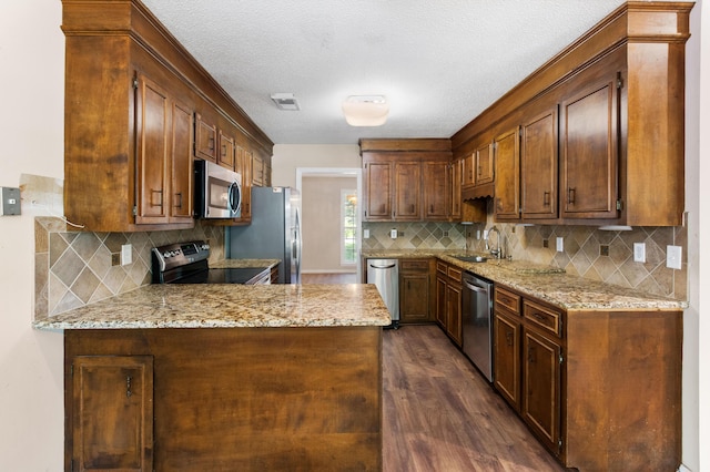 kitchen with stainless steel appliances, visible vents, a sink, and light stone countertops