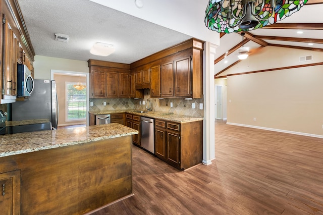 kitchen with tasteful backsplash, light stone counters, dark wood-style flooring, stainless steel appliances, and a sink