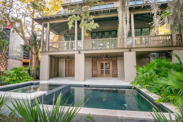 rear view of property with ceiling fan, a patio, a sunroom, a pool with hot tub, and a balcony