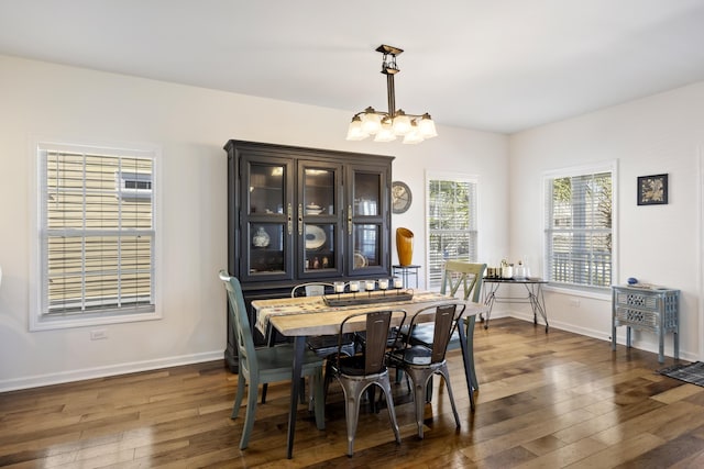 dining area with a notable chandelier, baseboards, and dark wood-style flooring