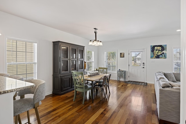 dining room with a chandelier, dark wood-style flooring, and baseboards