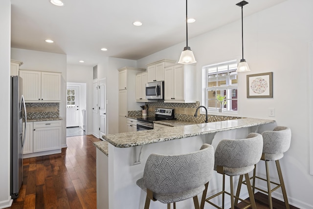 kitchen featuring stainless steel appliances, plenty of natural light, a peninsula, and light stone countertops