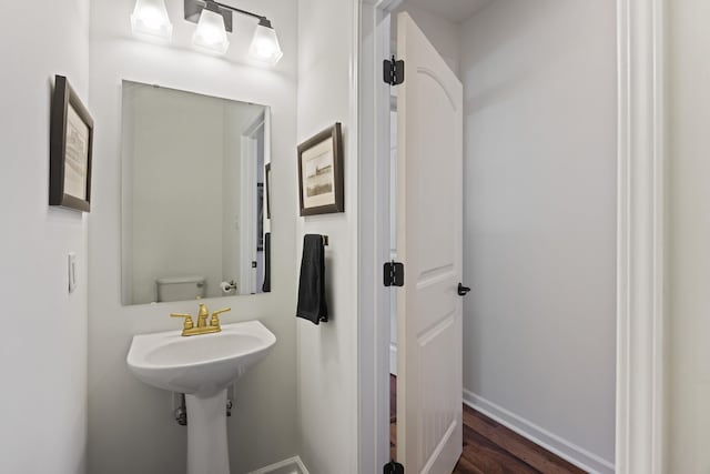 bathroom with wood finished floors, toilet, and baseboards