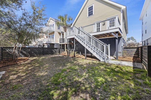 back of property with a fenced backyard, stairway, and a deck