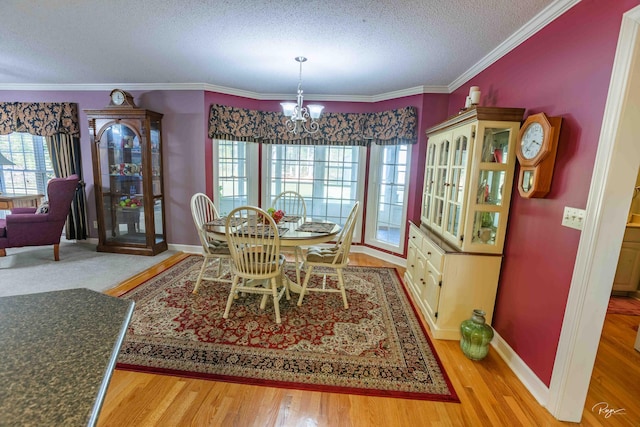 dining room with light wood-type flooring, a chandelier, a textured ceiling, and ornamental molding