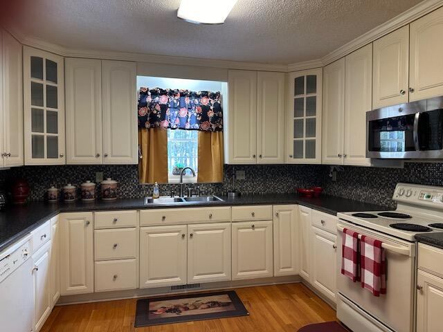 kitchen featuring white cabinets, white appliances, sink, and light hardwood / wood-style floors