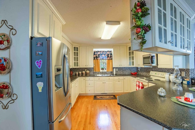 kitchen featuring backsplash, appliances with stainless steel finishes, white cabinets, kitchen peninsula, and light hardwood / wood-style flooring