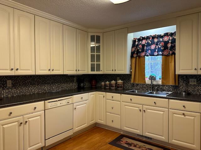 kitchen with a textured ceiling, sink, decorative backsplash, and dishwasher