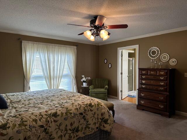 carpeted bedroom with a textured ceiling, ornamental molding, ceiling fan, and connected bathroom