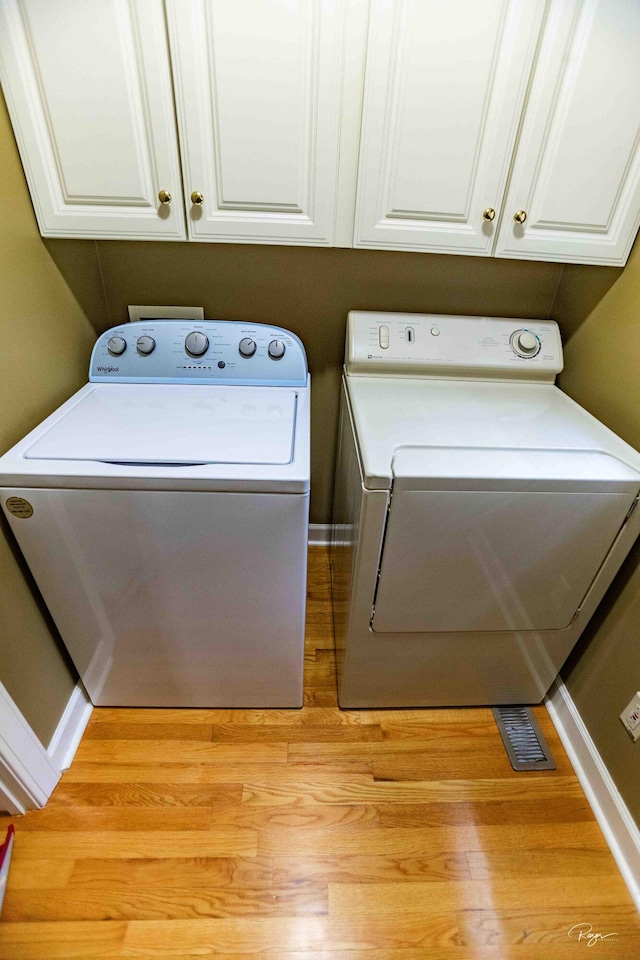 washroom with cabinets, separate washer and dryer, and light hardwood / wood-style flooring