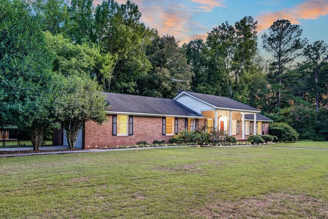 ranch-style house featuring a yard and brick siding