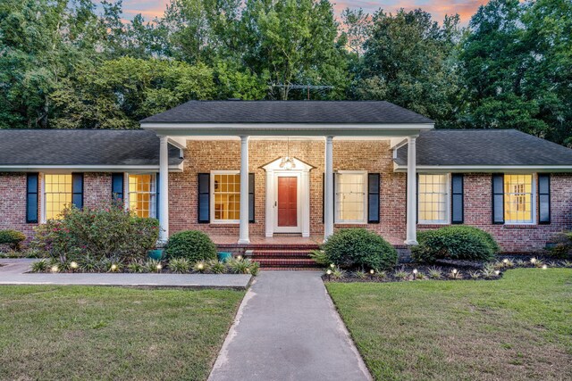 view of front of property with a front lawn, a porch, brick siding, and a shingled roof