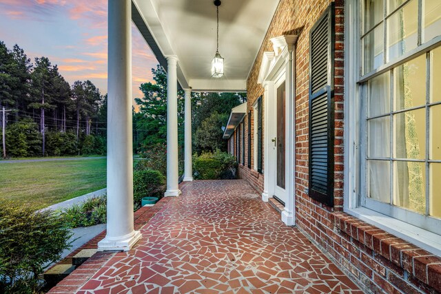 patio terrace at dusk with a yard and covered porch