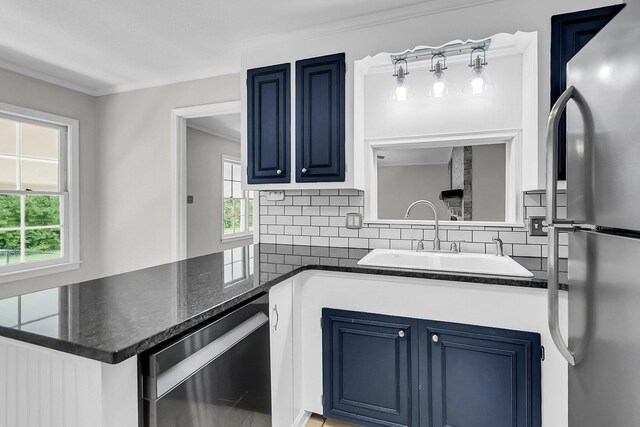 kitchen featuring blue cabinetry, decorative backsplash, appliances with stainless steel finishes, and a sink