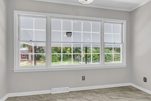 unfurnished room with baseboards, visible vents, and ornamental molding