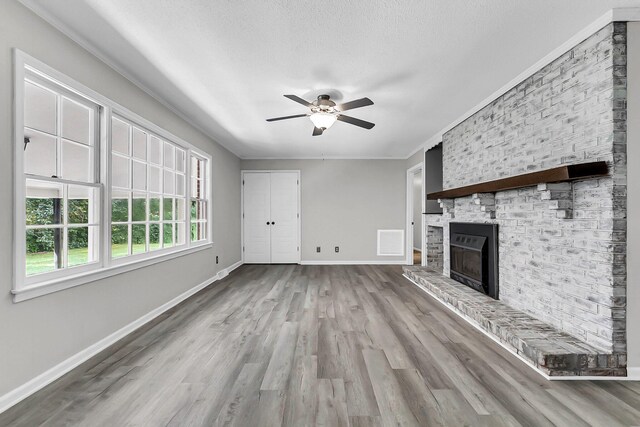 unfurnished living room featuring wood finished floors, visible vents, baseboards, crown molding, and a brick fireplace