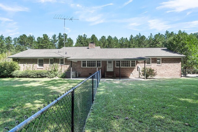 rear view of property featuring brick siding, a lawn, a chimney, a fenced backyard, and crawl space