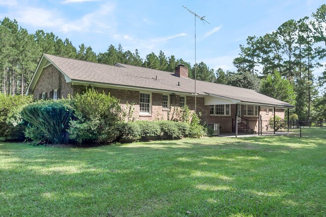 rear view of property featuring a lawn, brick siding, and a chimney