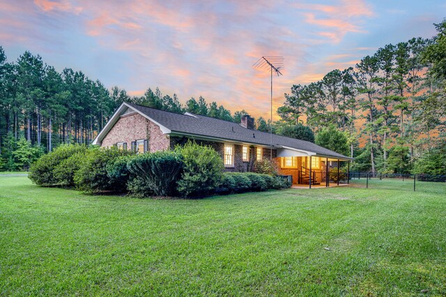 view of front of home with a lawn, a chimney, brick siding, and fence