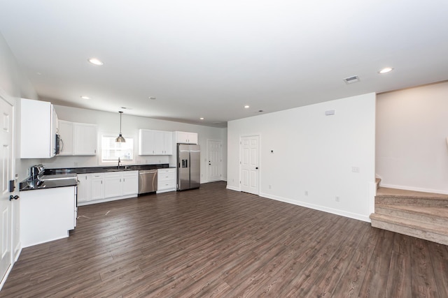 kitchen with dark countertops, open floor plan, dark wood-type flooring, decorative light fixtures, and stainless steel appliances