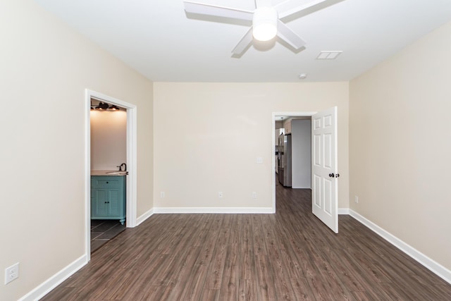 unfurnished bedroom with visible vents, baseboards, connected bathroom, dark wood-type flooring, and a sink