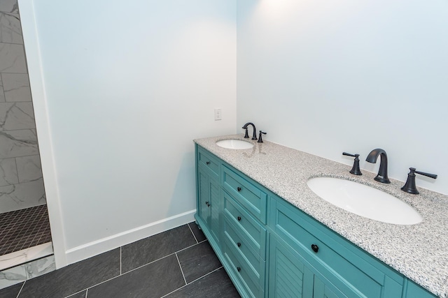 bathroom featuring baseboards, a sink, a marble finish shower, and double vanity