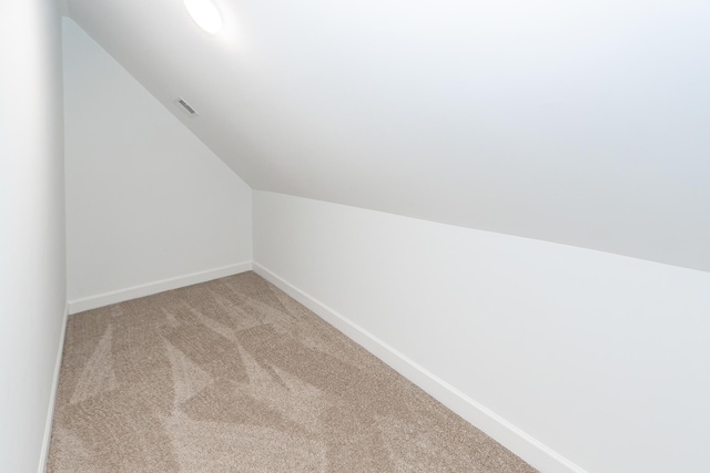 additional living space featuring carpet, visible vents, lofted ceiling, and baseboards