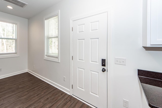 interior space with dark wood-type flooring, visible vents, and baseboards