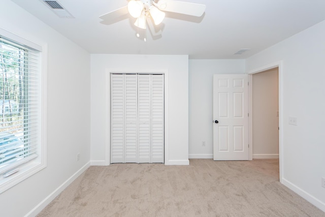 unfurnished bedroom featuring a closet, light colored carpet, visible vents, and baseboards