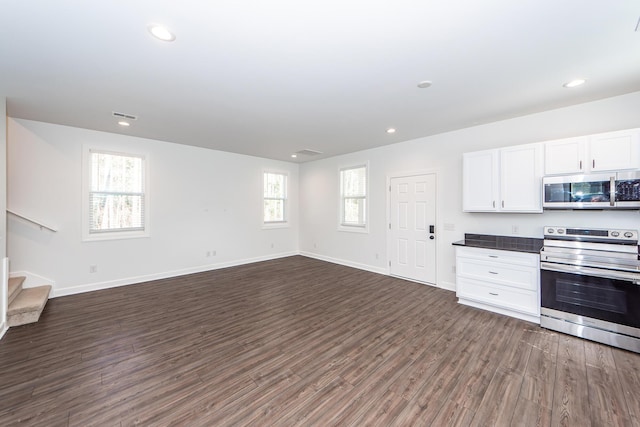 kitchen with dark wood-type flooring, visible vents, white cabinetry, appliances with stainless steel finishes, and dark countertops