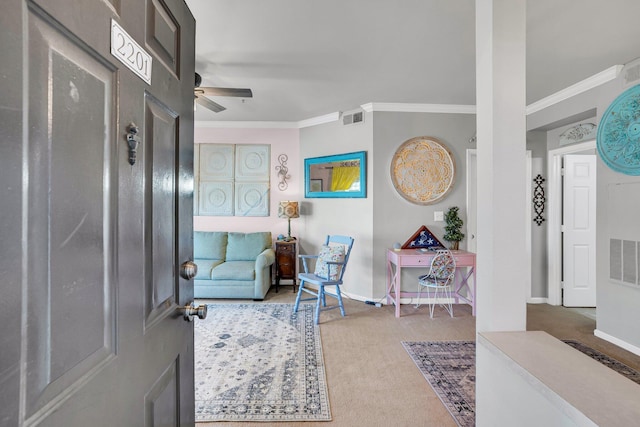 entryway with ceiling fan, ornamental molding, and carpet floors