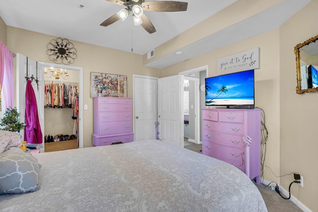 carpeted bedroom with ceiling fan with notable chandelier, a closet, and a spacious closet