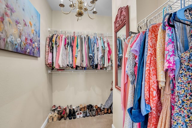 spacious closet featuring an inviting chandelier and carpet