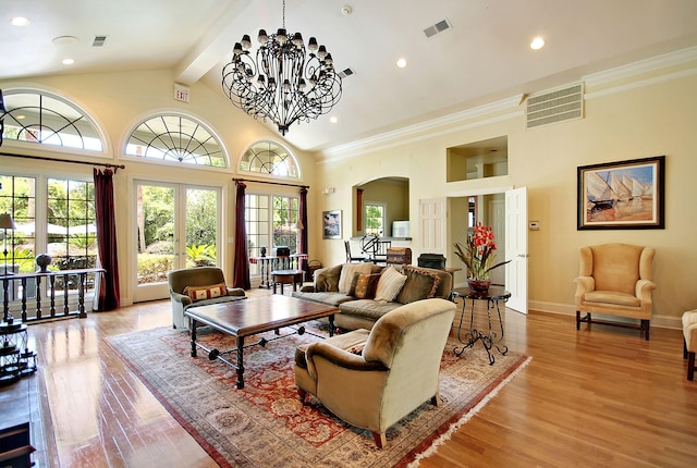 living room with an inviting chandelier, beam ceiling, light hardwood / wood-style floors, and french doors