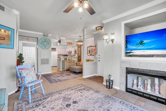 living room with tile patterned flooring, ceiling fan, crown molding, and a fireplace