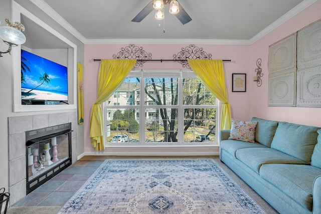 living room with ceiling fan, ornamental molding, and a tiled fireplace