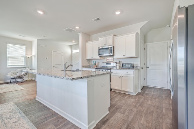 kitchen featuring light hardwood / wood-style flooring, stainless steel appliances, white cabinets, and a kitchen island with sink