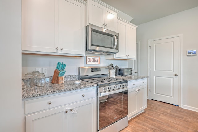 kitchen with light hardwood / wood-style flooring, stainless steel appliances, white cabinets, and light stone counters