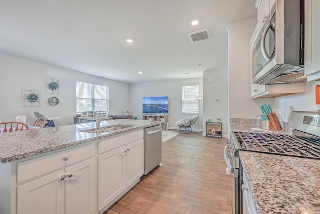 kitchen with sink, light hardwood / wood-style flooring, white cabinetry, appliances with stainless steel finishes, and a wealth of natural light