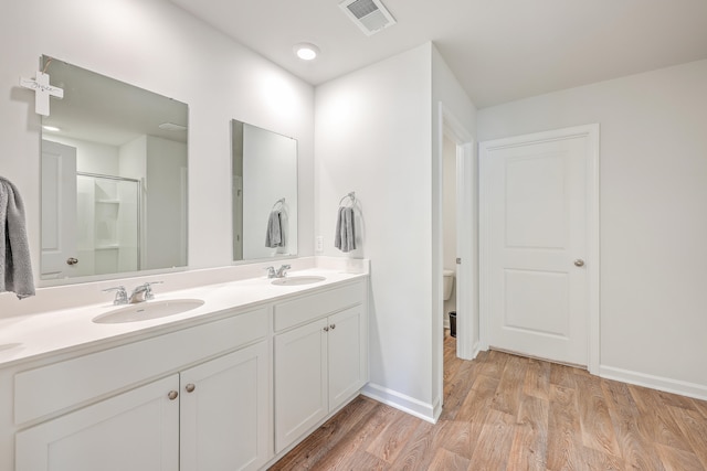 bathroom with hardwood / wood-style flooring, vanity, toilet, and a shower with shower door