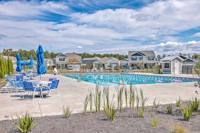 view of swimming pool with a storage shed and a patio area