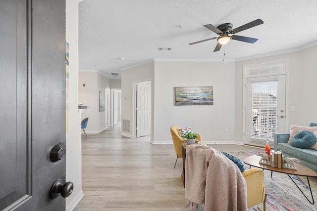 living room featuring ornamental molding, ceiling fan, a textured ceiling, and light wood-type flooring