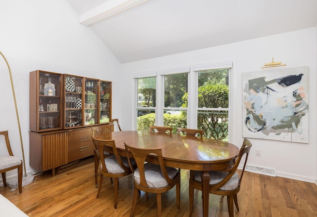 dining room with lofted ceiling with beams, wood finished floors, visible vents, and baseboards