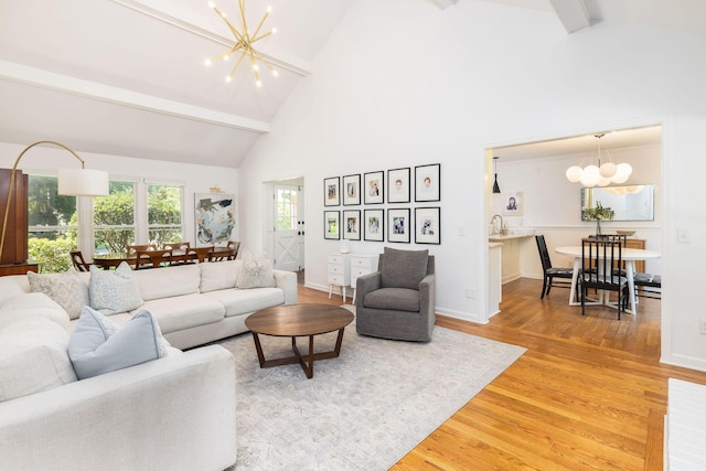 living room featuring baseboards, a chandelier, light wood-type flooring, high vaulted ceiling, and beam ceiling