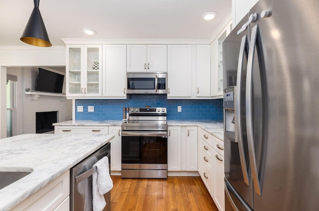 kitchen featuring appliances with stainless steel finishes, white cabinets, glass insert cabinets, and hanging light fixtures