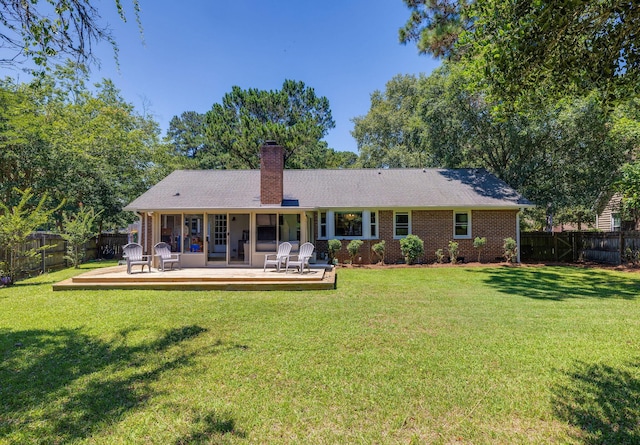 back of house featuring a fenced backyard, a yard, a chimney, and brick siding